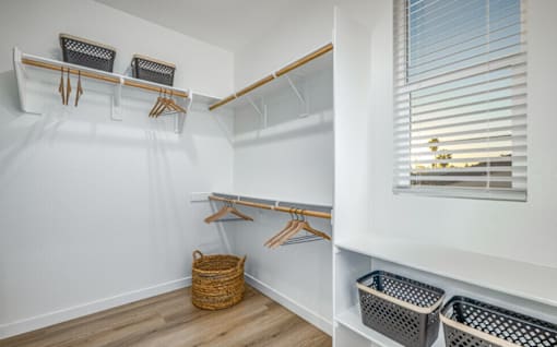 A white closet with a window and a basket on the floor.