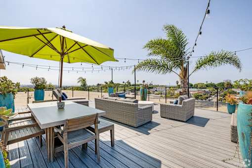 A wooden table with chairs and a yellow umbrella on a wooden deck.