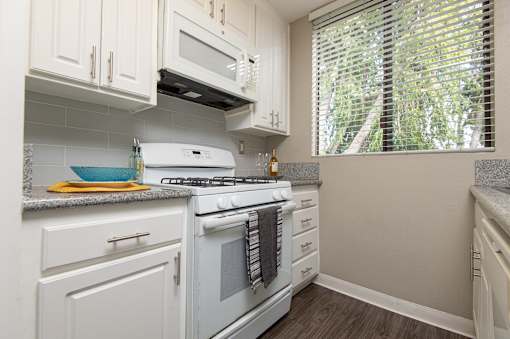 A white stove and microwave in a kitchen with white cabinets.