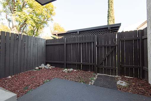 A black fence with a gate and a small garden in front.