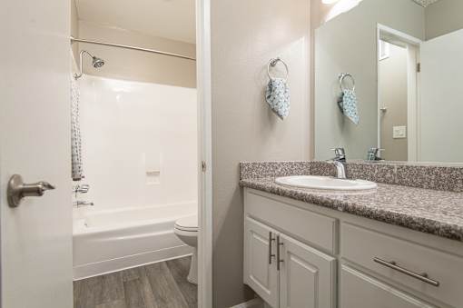 A bathroom with a sink, mirror, and bathtub.
