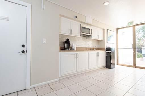 A kitchen with white cabinets and a white door.