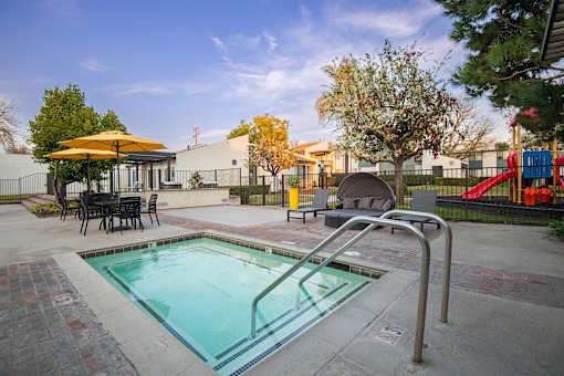 A small pool with a metal ladder and a table with chairs around it.