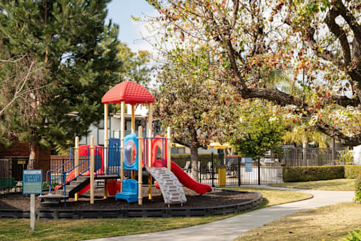 A playground with a red and blue slide and a red and yellow tower.