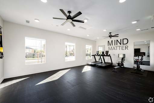 A spacious room with a ceiling fan and exercise equipment.