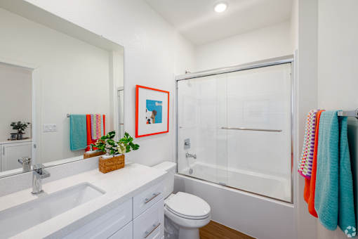 A white bathroom with a toilet, sink, and shower.