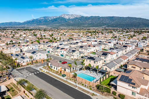 A suburban neighborhood with houses and a street in the foreground.