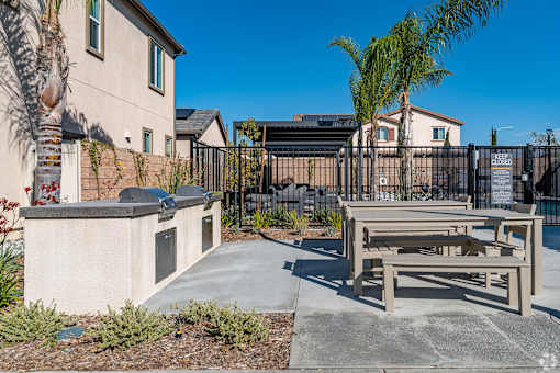 A concrete bench is in front of a black fence.
