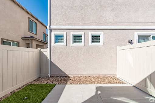 A beige house with a white fence and a small garden.