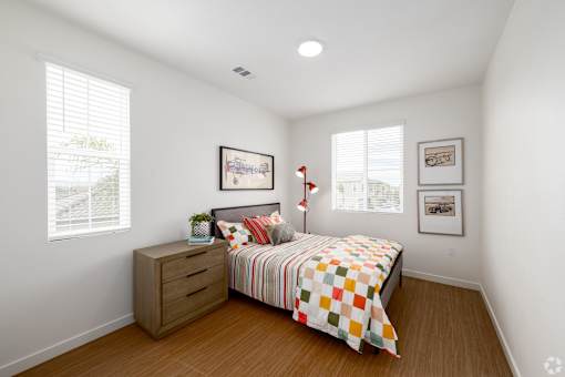 A bedroom with a bed, dresser, and two pictures on the wall.