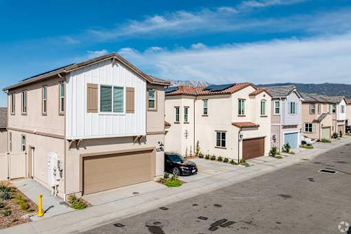 A row of houses with a car parked in front of the first house.