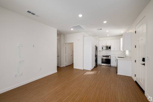 A kitchen with white cabinets and a wooden floor.