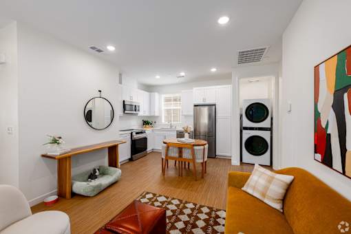 A modern kitchen with a yellow couch and a painting on the wall.