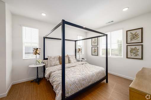 A bedroom with a four poster bed and a nightstand with a lamp.