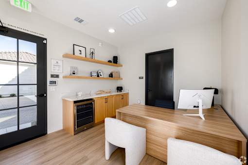 A modern office with a wooden desk and white chairs.