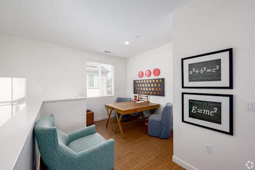 A room with a chair, table, and two framed equations on the wall.