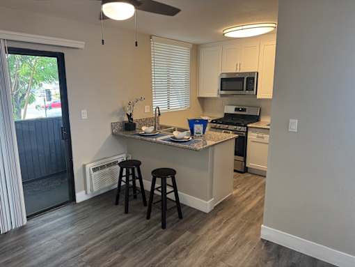 A kitchen with a white counter and black stools.