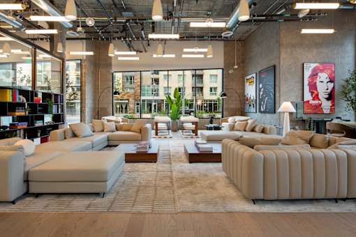 A large, modern living room with a variety of seating options and a view of the city.