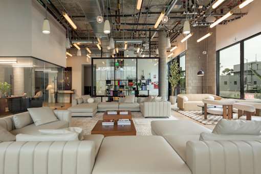 A modern living room with white furniture and a glass wall.