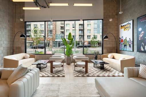 A living room with a large window, a couch, a chair, and a coffee table.