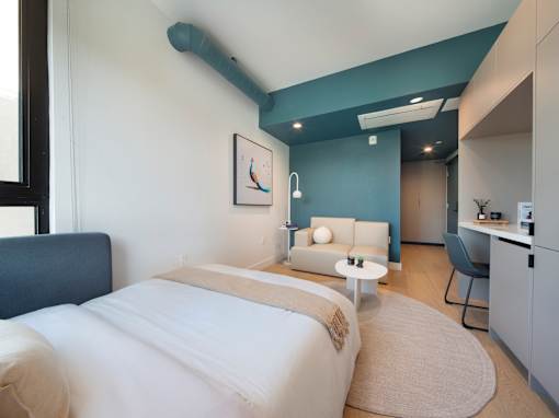 A bedroom with a bed, a chair, and a painting on the wall.