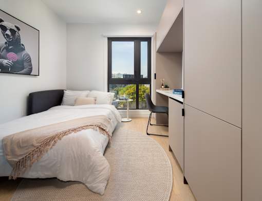 A bedroom with a large bed and a window overlooking the city.
