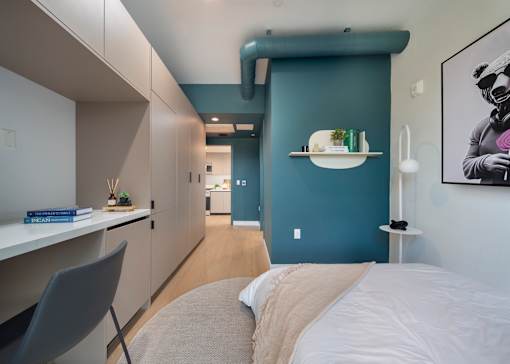 A modern bedroom with a bed, chair, and a painting on the wall.