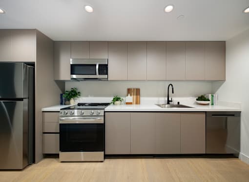 A modern kitchen with a stainless steel refrigerator, a microwave above the stove, and a sink with a faucet.
