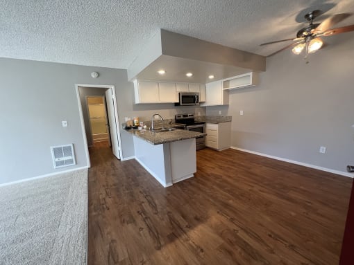 the view of a kitchen and living room from the entryway of an empty house