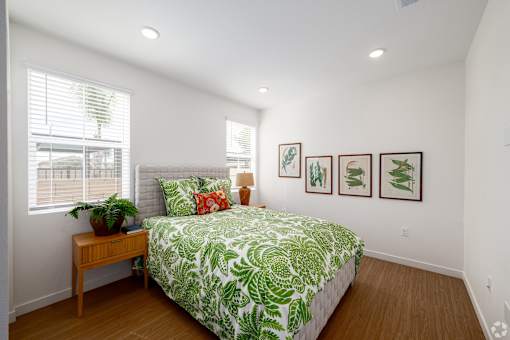 A bedroom with a bed, a table, and pictures on the wall.