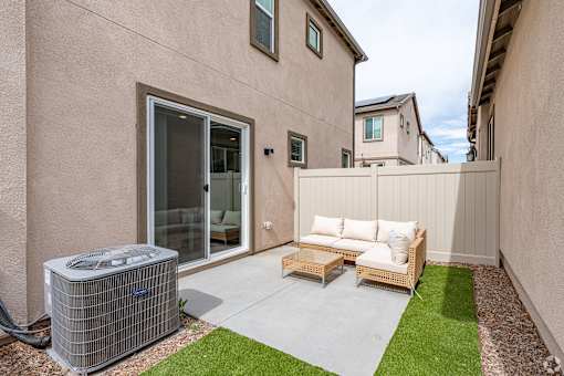A patio with a couch, chairs, and an air conditioning unit.