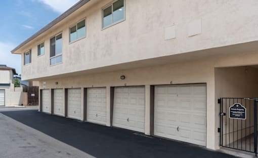 A building with a row of garage doors and a sign on the gate.