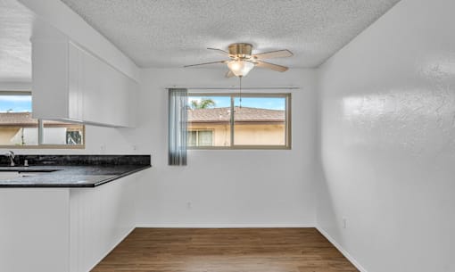 A room with a ceiling fan and a window overlooking a building.