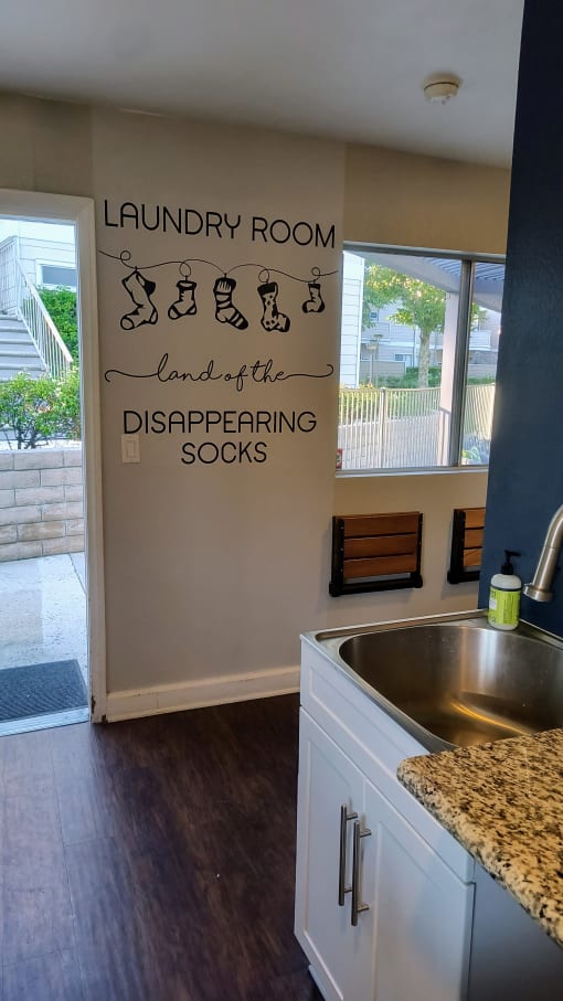 a kitchen with a sink and a wall that says laundry room land of the disappearing socks