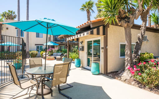 A patio with a table and chairs under a blue umbrella.