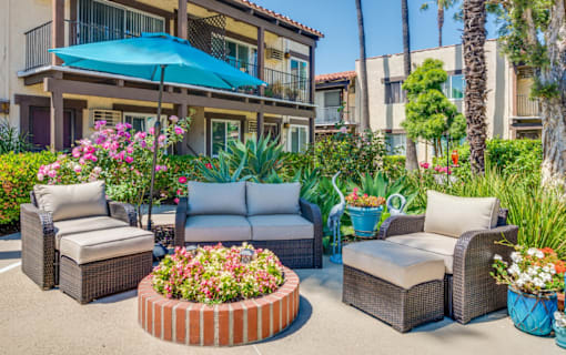 A patio with a blue umbrella and furniture.