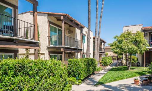 A row of apartment buildings with green bushes in front.