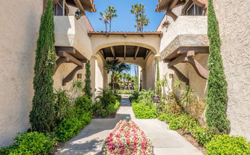 A garden pathway leads to a building with arches.