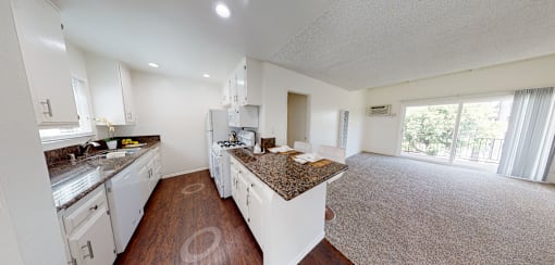 A kitchen with white cabinets and a granite countertop.