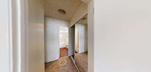 A hallway with white walls and a brown carpet.