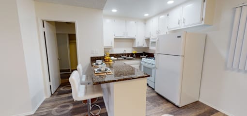 A kitchen with white cabinets and a white refrigerator.
