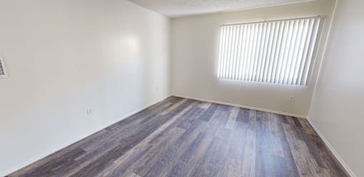 A room with a window and wooden flooring.