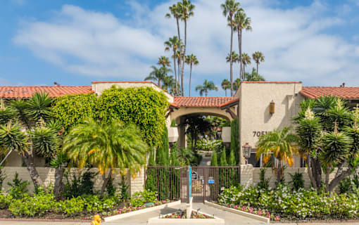 A building with a gate and palm trees in front.
