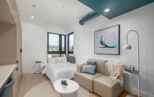 A bedroom with a large bed and a couch with a painting on the wall.