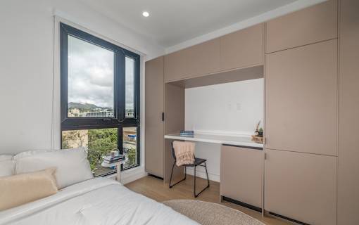 A bedroom with a large bed and a desk with a chair.