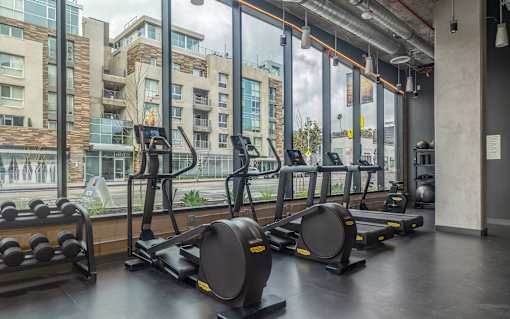 A gym with a view of apartment buildings outside the window.