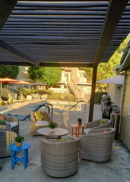 a patio with wicker furniture and a pool in the background