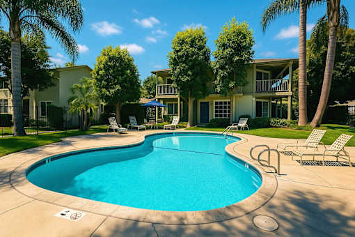 A swimming pool surrounded by palm trees and lounge chairs.