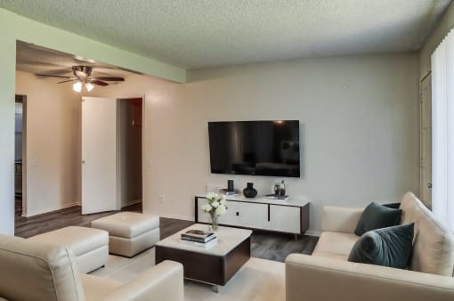 a living room with white couches and a tv on the wall