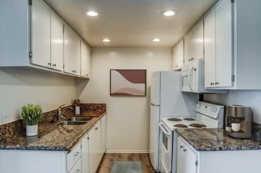 a kitchen with white appliances and granite counter tops